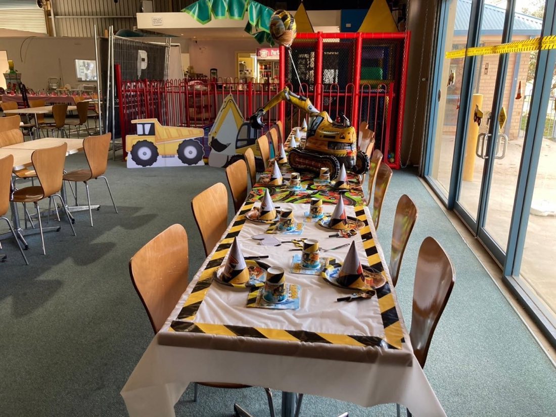 A construction-themed birthday party room at Rumble Tumbles with an inflatable excavator and themed table setup