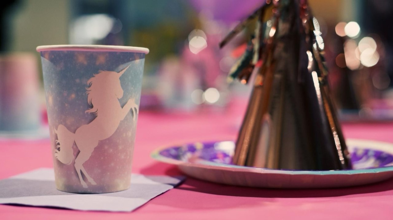 Unicorn party cup detail on a pink-tableclothed birthday table